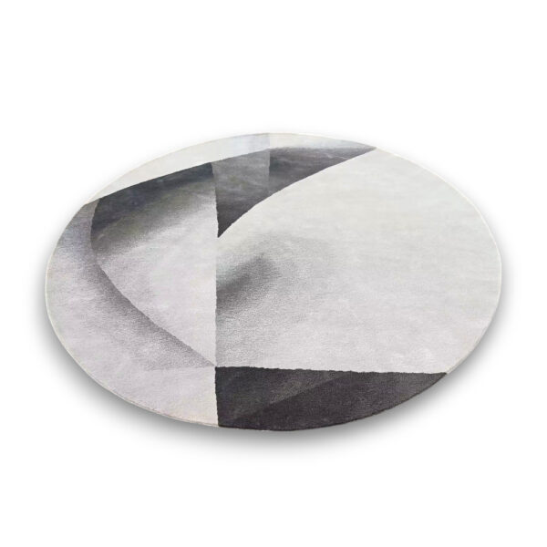 Custom tufted round rug featuring geometric design in grey, white and charcoal with angular shapes