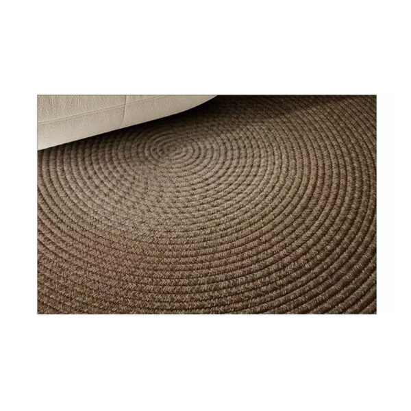 Custom woven gluefree round wool rug showing brown concentric circle pattern with rope-like texture under white furniture leg